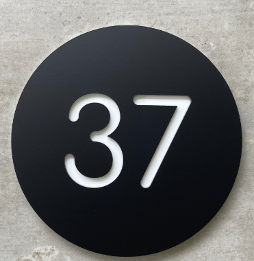 Round black house number plate showing a white 37