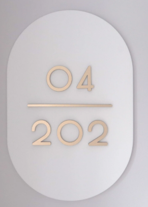 Rounded white unit number plate with brushed gold 04 above 202