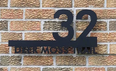 Cut-out house number and street name in script mounted on brickwork